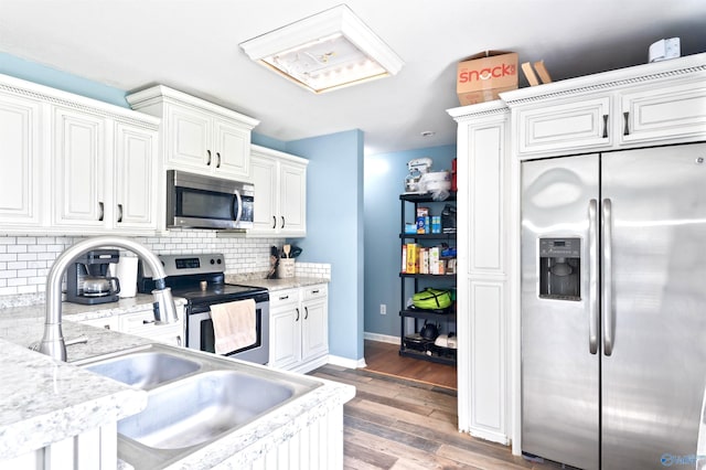 kitchen with appliances with stainless steel finishes, dark hardwood / wood-style flooring, backsplash, sink, and white cabinetry