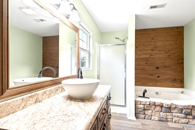 bathroom with vanity, wooden walls, hardwood / wood-style floors, and plus walk in shower