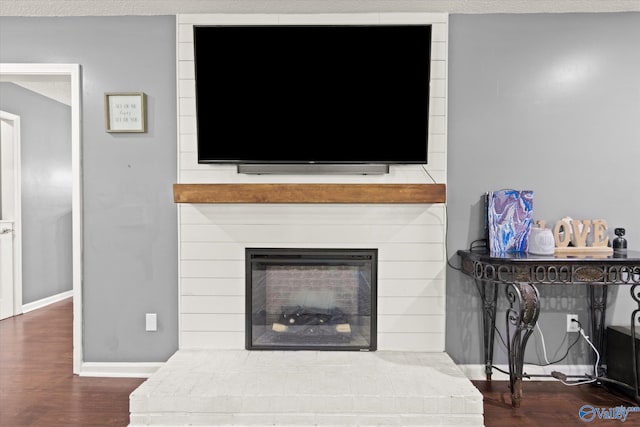 room details with hardwood / wood-style floors, a textured ceiling, and a brick fireplace