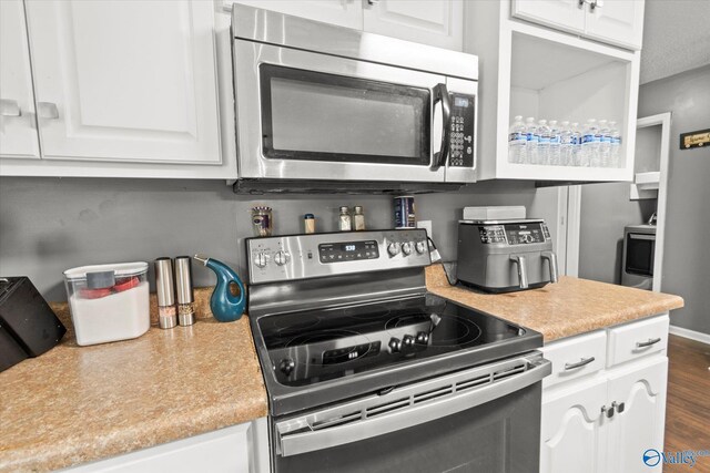 kitchen featuring dark hardwood / wood-style flooring, appliances with stainless steel finishes, and white cabinets