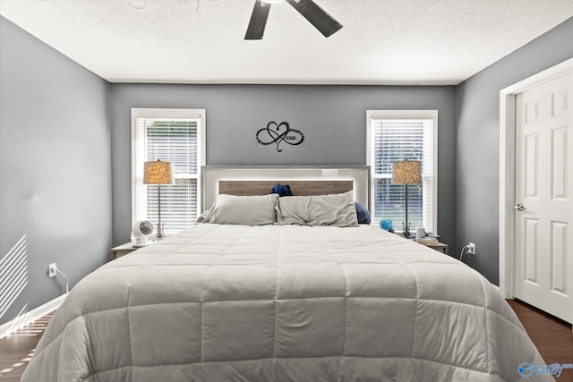 bedroom with dark wood-type flooring, ceiling fan, and a textured ceiling