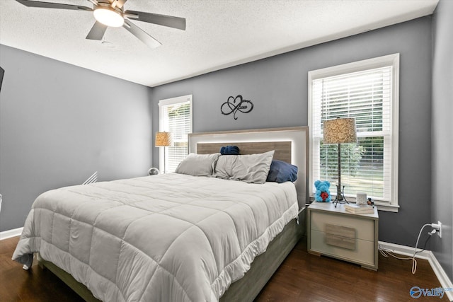 bedroom with a textured ceiling, ceiling fan, and dark hardwood / wood-style floors