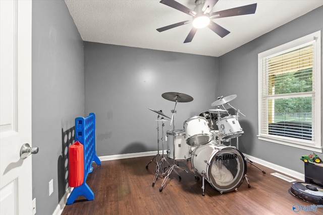 workout room with a textured ceiling, dark wood-type flooring, and ceiling fan