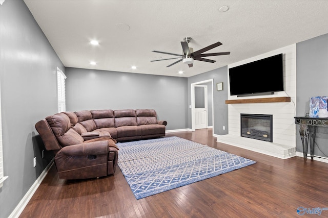 living room featuring a textured ceiling, ceiling fan, wood-type flooring, and a fireplace