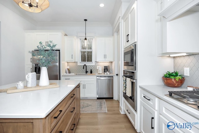 kitchen featuring stainless steel appliances, light hardwood / wood-style flooring, pendant lighting, and white cabinets