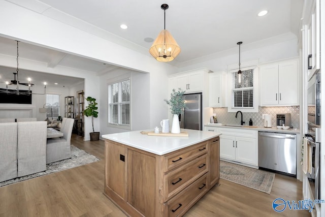 kitchen with a kitchen island, tasteful backsplash, white cabinets, appliances with stainless steel finishes, and light hardwood / wood-style floors