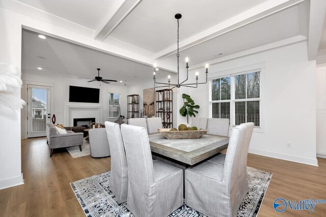 dining space with beam ceiling, ceiling fan with notable chandelier, and wood-type flooring