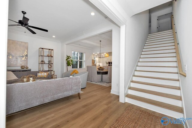 interior space with crown molding, ceiling fan with notable chandelier, and wood-type flooring