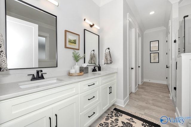 bathroom featuring crown molding, wood-type flooring, and vanity