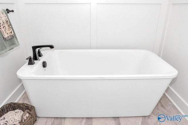 bathroom with a washtub and tile patterned flooring