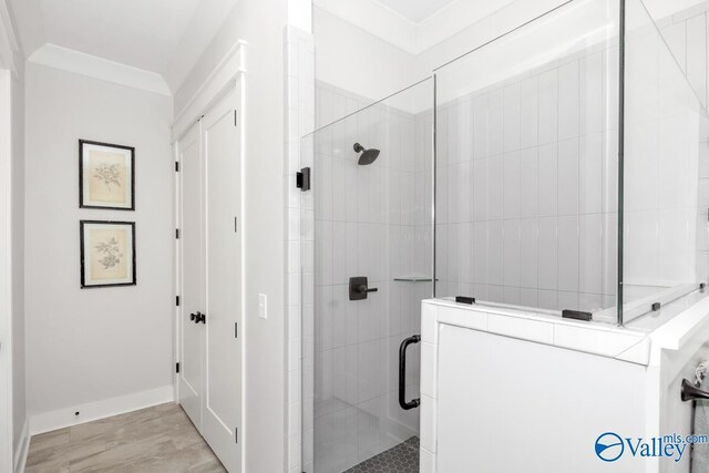 bathroom featuring tile patterned flooring, ornamental molding, and a shower with shower door