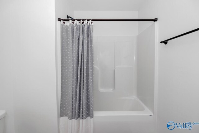 bathroom with toilet and shower / tub combo with curtain