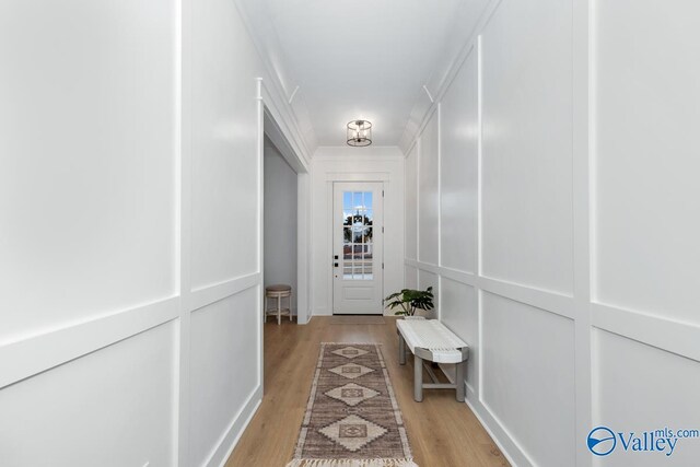 corridor featuring light wood-type flooring and ornamental molding