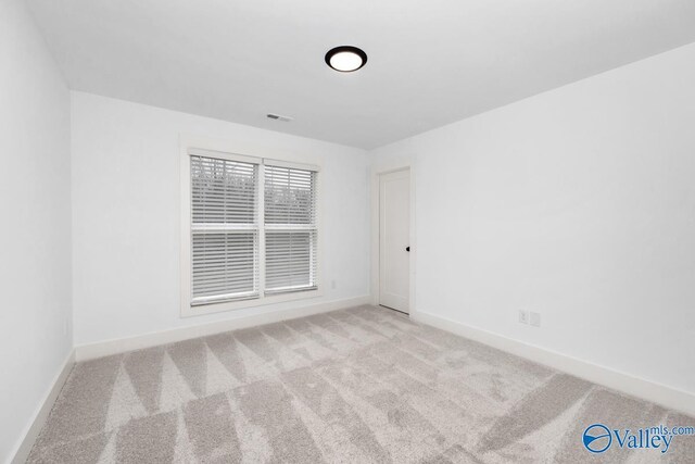 spare room featuring light carpet