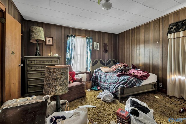 carpeted bedroom featuring wood walls