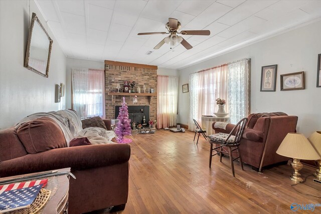 living room with plenty of natural light, ceiling fan, a brick fireplace, and wood-type flooring