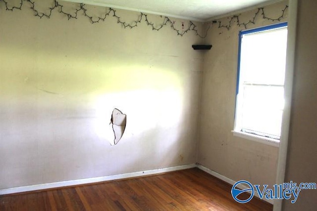 unfurnished room with plenty of natural light, baseboards, and wood finished floors