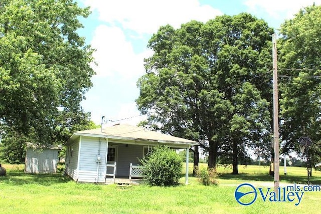 back of property featuring covered porch, a lawn, a storage shed, and an outdoor structure