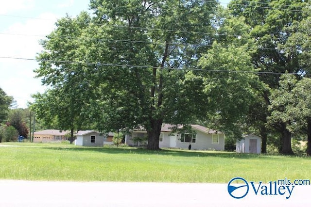 view of front of house with a storage unit, an outbuilding, and a front yard