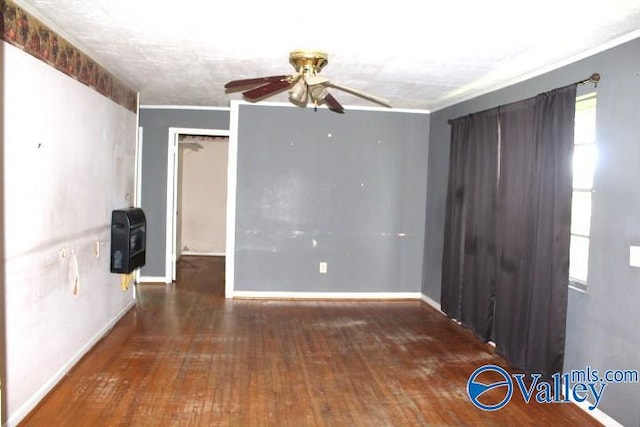 unfurnished room featuring heating unit, baseboards, ceiling fan, and wood-type flooring