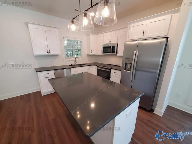 kitchen with pendant lighting, stainless steel appliances, white cabinets, and a center island