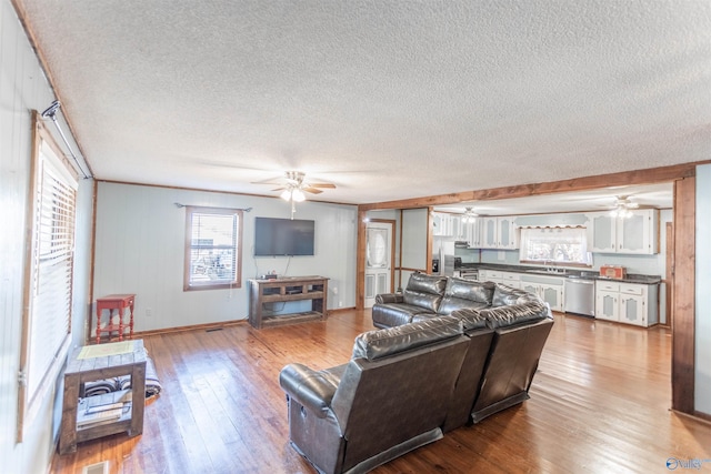 living room featuring a healthy amount of sunlight, a textured ceiling, hardwood / wood-style floors, and ceiling fan