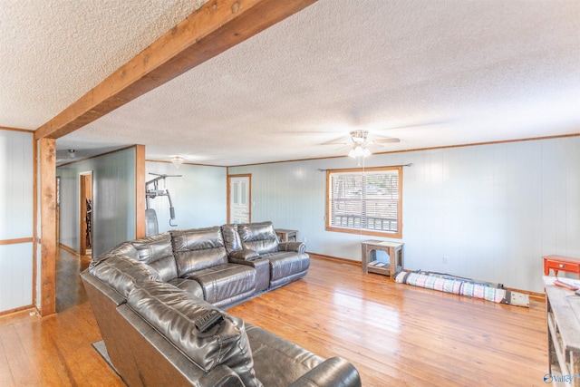 living room with ceiling fan, beamed ceiling, a textured ceiling, and hardwood / wood-style flooring