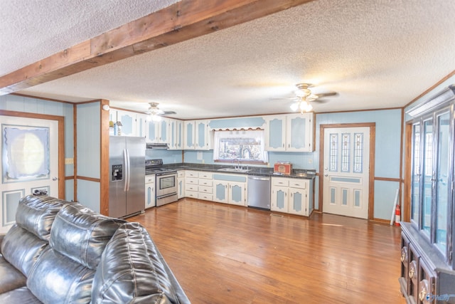 kitchen with sink, appliances with stainless steel finishes, hardwood / wood-style flooring, and white cabinets