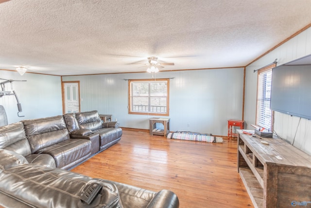 living room with a textured ceiling, ceiling fan, hardwood / wood-style floors, and crown molding