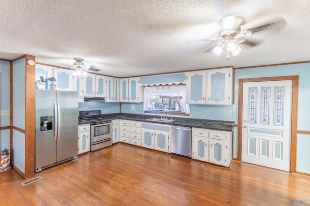 kitchen featuring a textured ceiling, white cabinets, appliances with stainless steel finishes, wood-type flooring, and sink