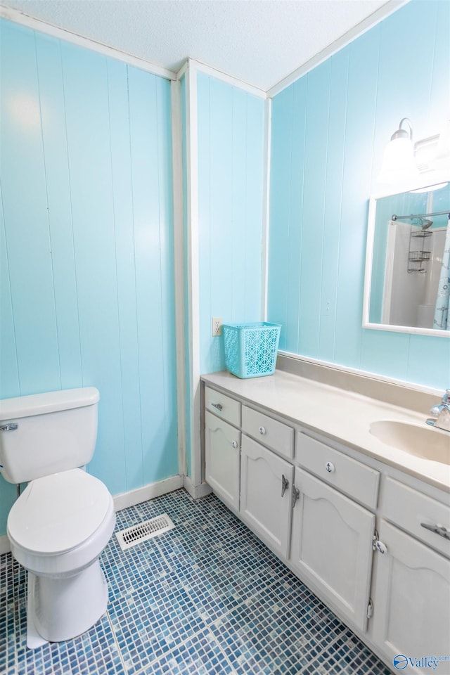 bathroom with tile patterned floors, toilet, vanity, and a textured ceiling