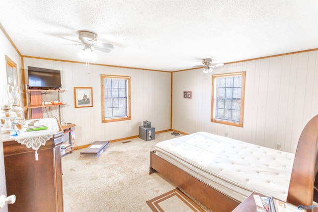 bedroom featuring ornamental molding, a textured ceiling, light colored carpet, and ceiling fan