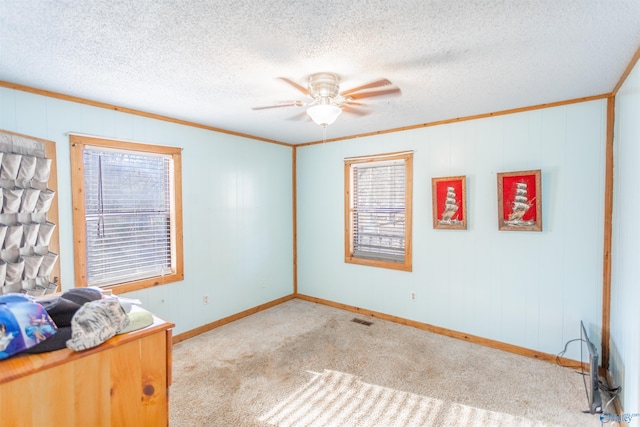 carpeted empty room featuring crown molding, a textured ceiling, and ceiling fan