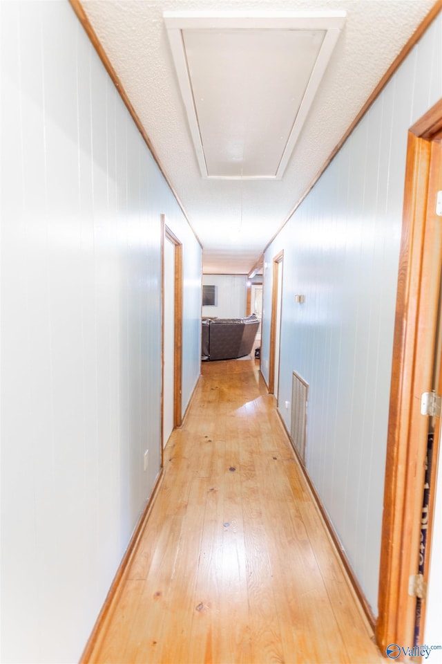 hallway with light hardwood / wood-style floors and a textured ceiling