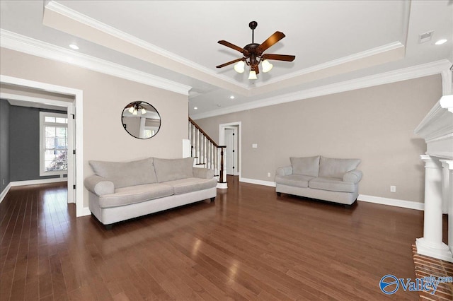 living room featuring a raised ceiling, dark hardwood / wood-style flooring, and ornamental molding