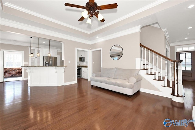 unfurnished living room with crown molding, ceiling fan, and dark wood-type flooring