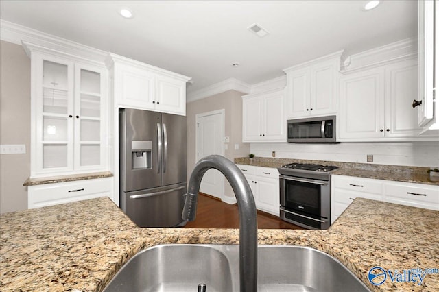 kitchen with light stone countertops, white cabinetry, sink, stainless steel appliances, and crown molding