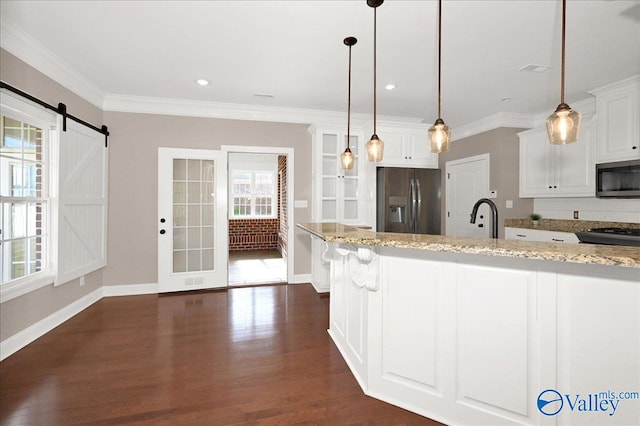 kitchen featuring white cabinets, a barn door, light stone countertops, and stainless steel appliances