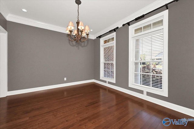 spare room featuring a barn door, dark hardwood / wood-style flooring, a notable chandelier, and ornamental molding