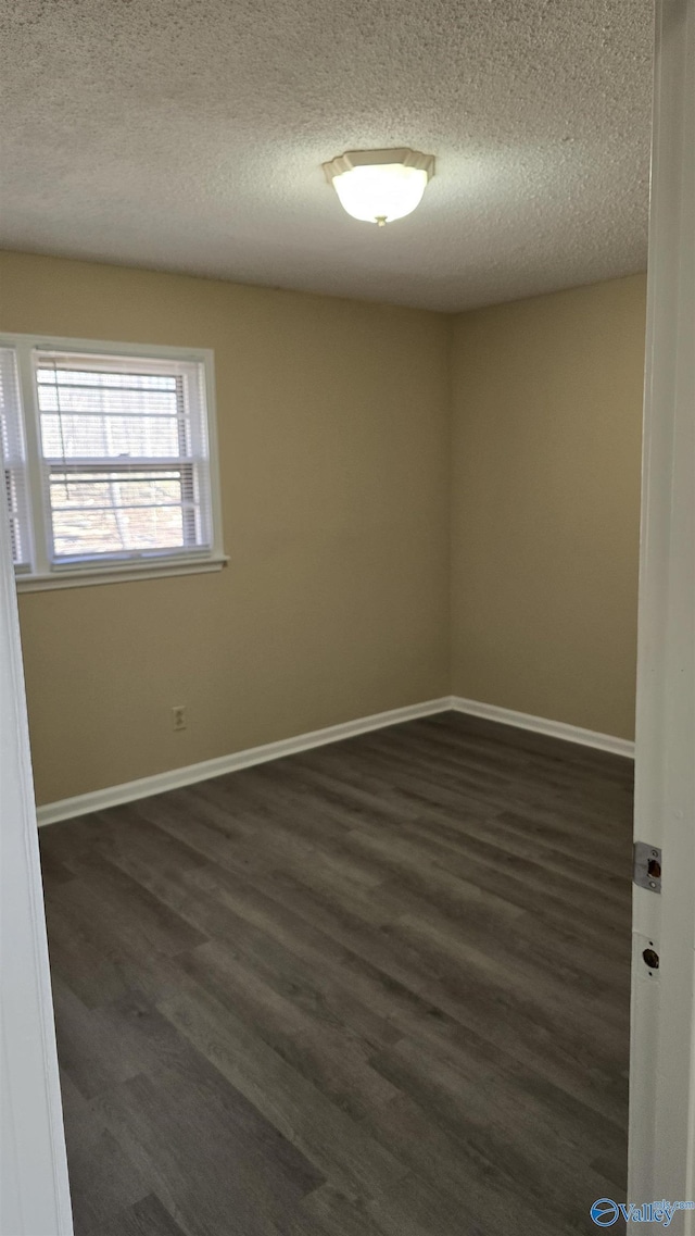 unfurnished room featuring dark wood-type flooring and a textured ceiling