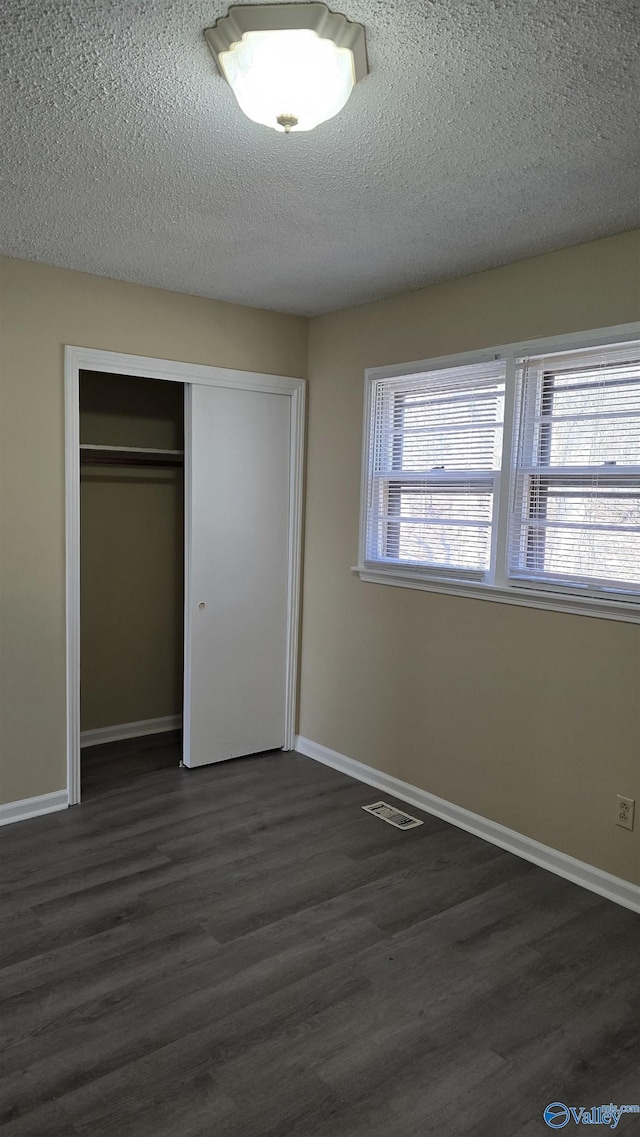 unfurnished bedroom featuring dark wood-type flooring, a closet, and a textured ceiling