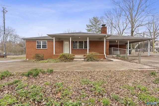 view of front of house with a chimney, concrete driveway, brick siding, and fence