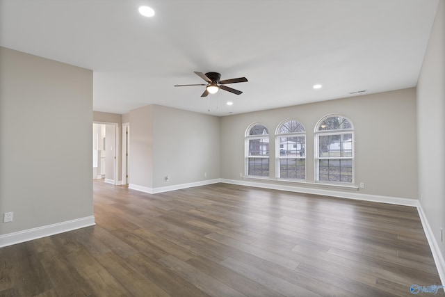 unfurnished room featuring a ceiling fan, dark wood-type flooring, baseboards, and visible vents