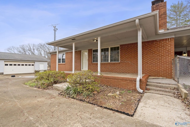 view of front of house with an outbuilding, a porch, a chimney, a garage, and brick siding