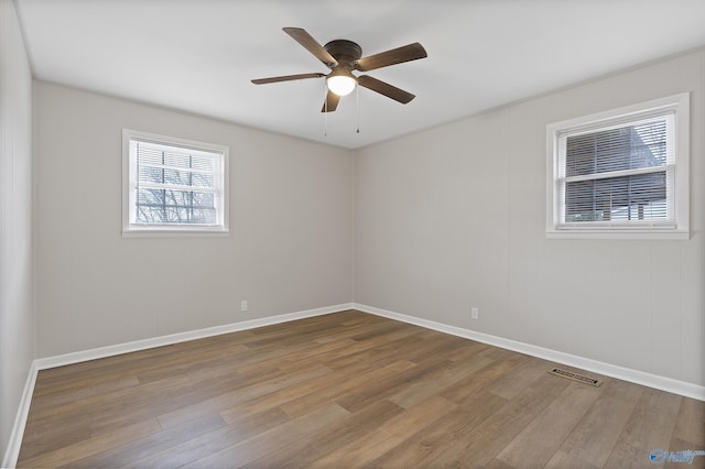 unfurnished room featuring visible vents, baseboards, wood finished floors, and a ceiling fan