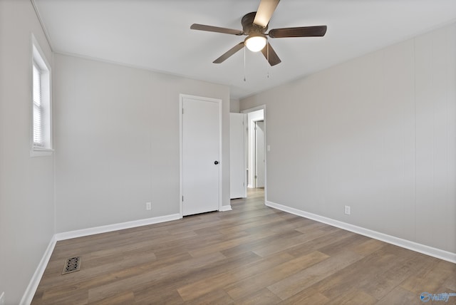 empty room with visible vents, baseboards, wood finished floors, and a ceiling fan