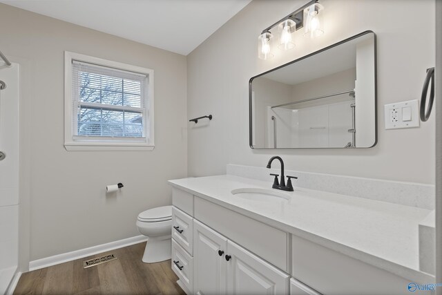 bathroom with vanity, wood finished floors, visible vents, walk in shower, and toilet