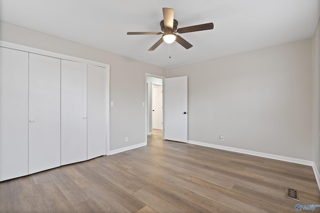 unfurnished bedroom with visible vents, a ceiling fan, wood finished floors, a closet, and baseboards