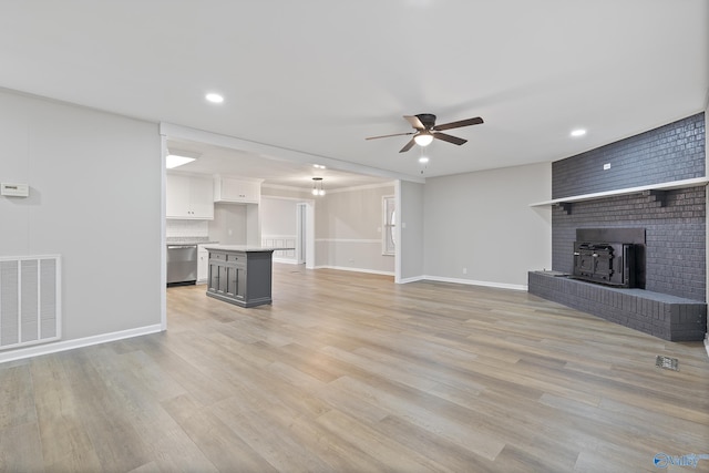 unfurnished living room with visible vents, light wood-style flooring, baseboards, and a ceiling fan