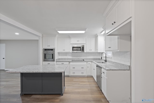 kitchen featuring appliances with stainless steel finishes, white cabinetry, and a sink